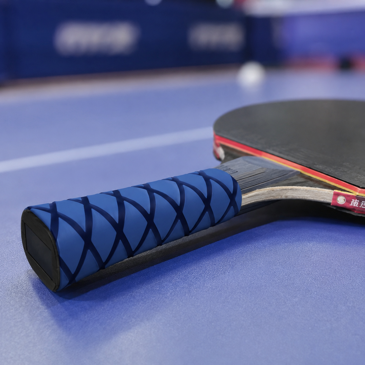 Manchon thermorétractable bleu à motif losange installé sur le manche d'une raquette de tennis de table