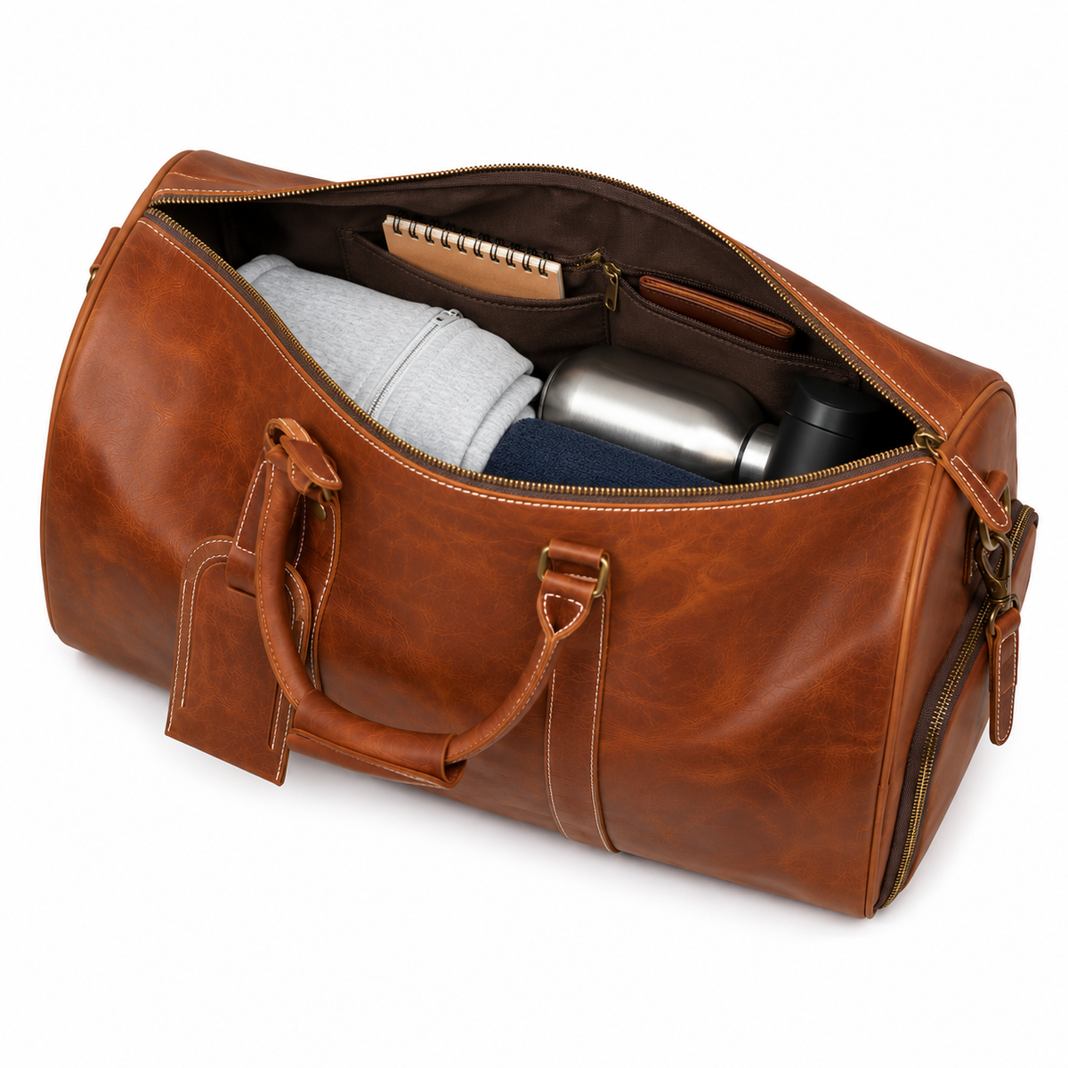 Compartiment principal ouvert du sac en cuir avec vêtements, carnet et thermos rangés à l'intérieur