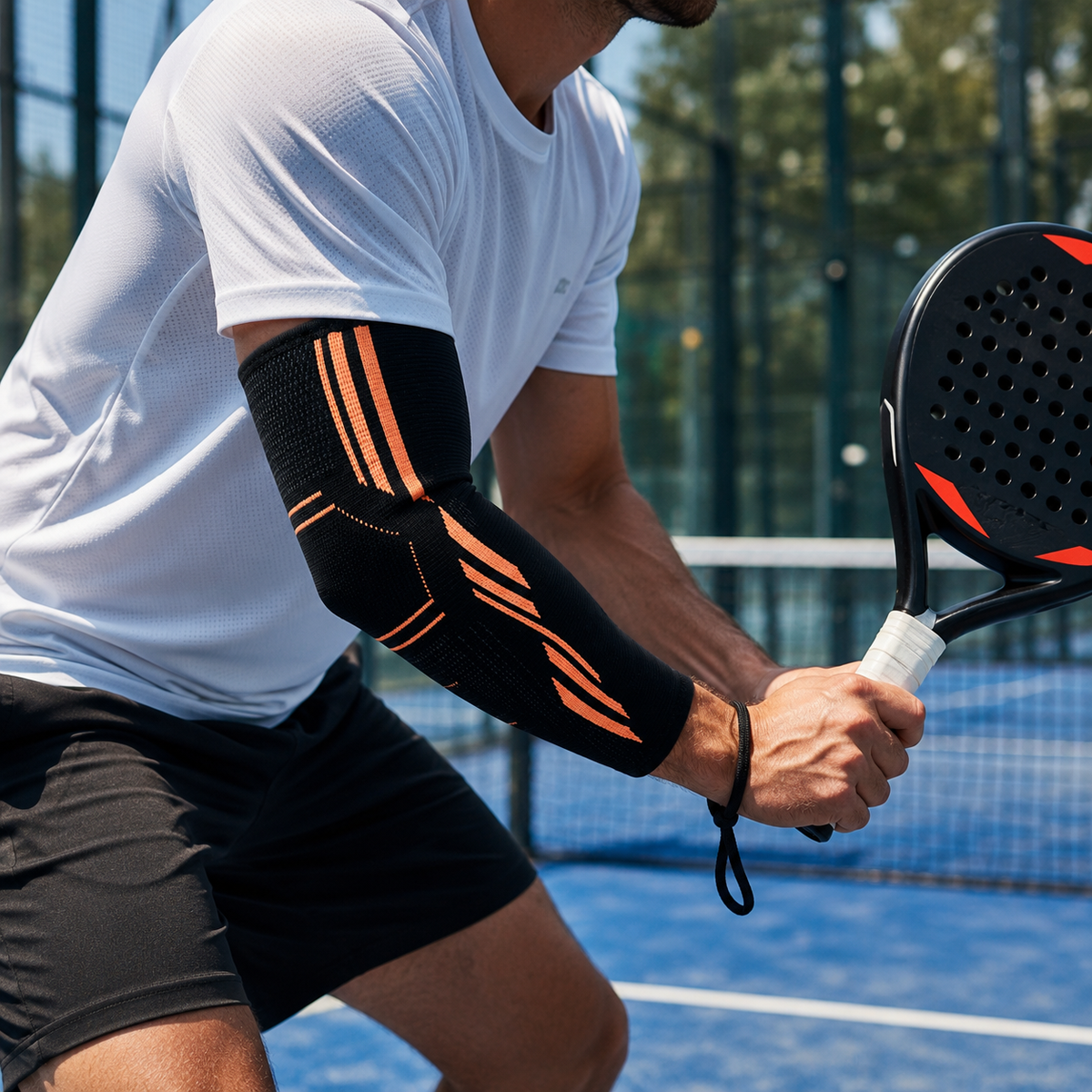 Joueur de padel portant le manchon de compression noir et orange au coude pendant un match