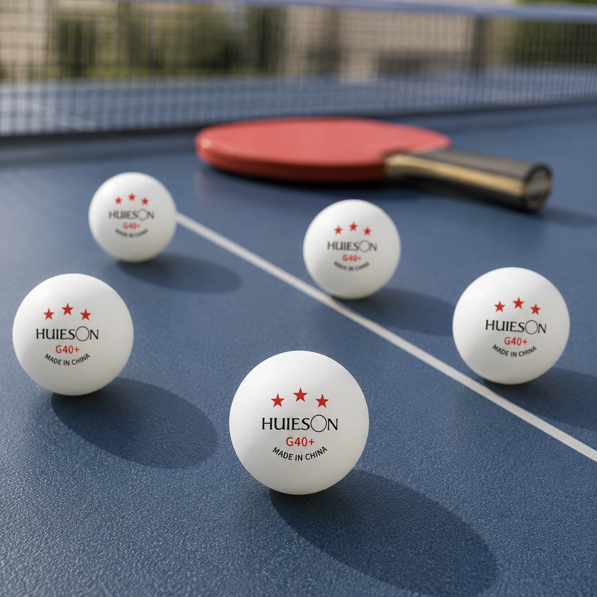 Balles de tennis de table Huieson blanches disposées sur une table avec une raquette