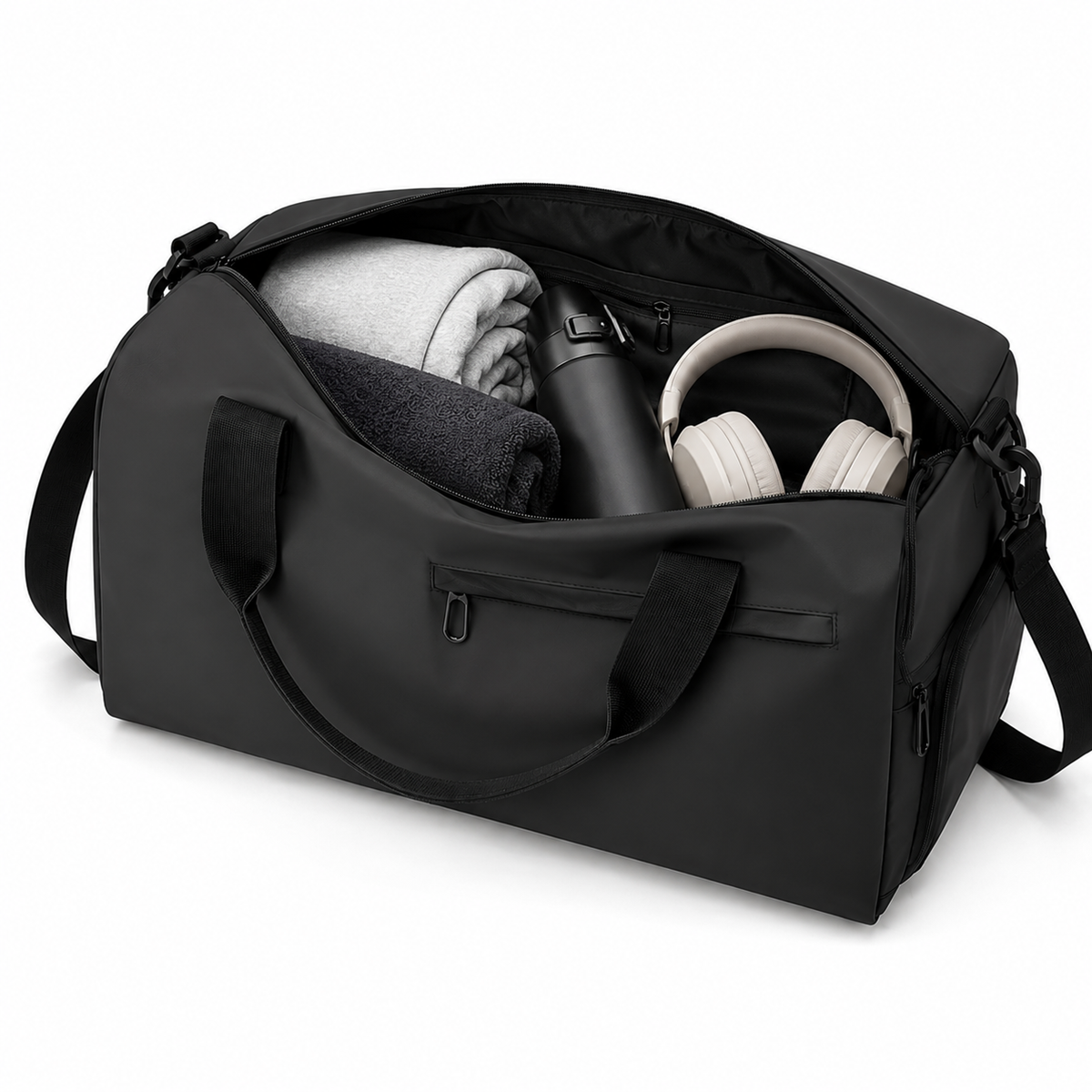 Compartiment principal ouvert du sac noir avec serviette, gourde et casque audio rangés à l'intérieur